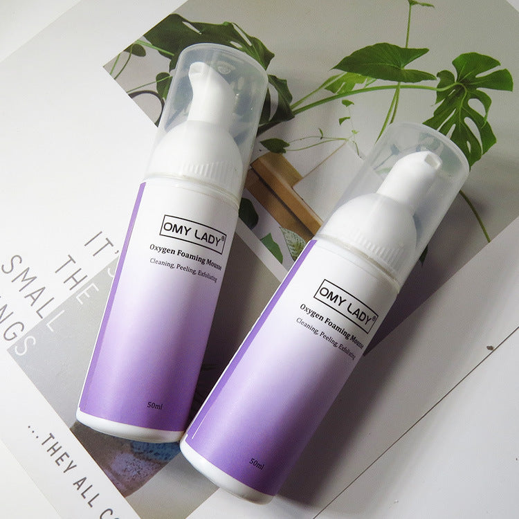 Two bottles of OMY LADY Cleansing Mousse 50ml placed on a magazine, showcasing its sleek packaging and oil control skincare benefits.